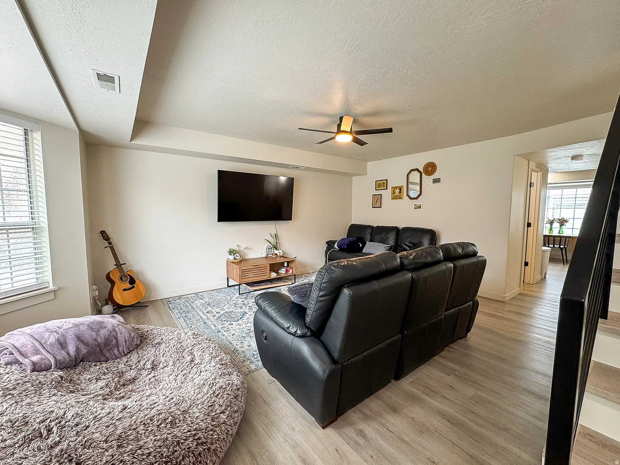 Living area with light wood finished floors, a textured ceiling, and ceiling fan
