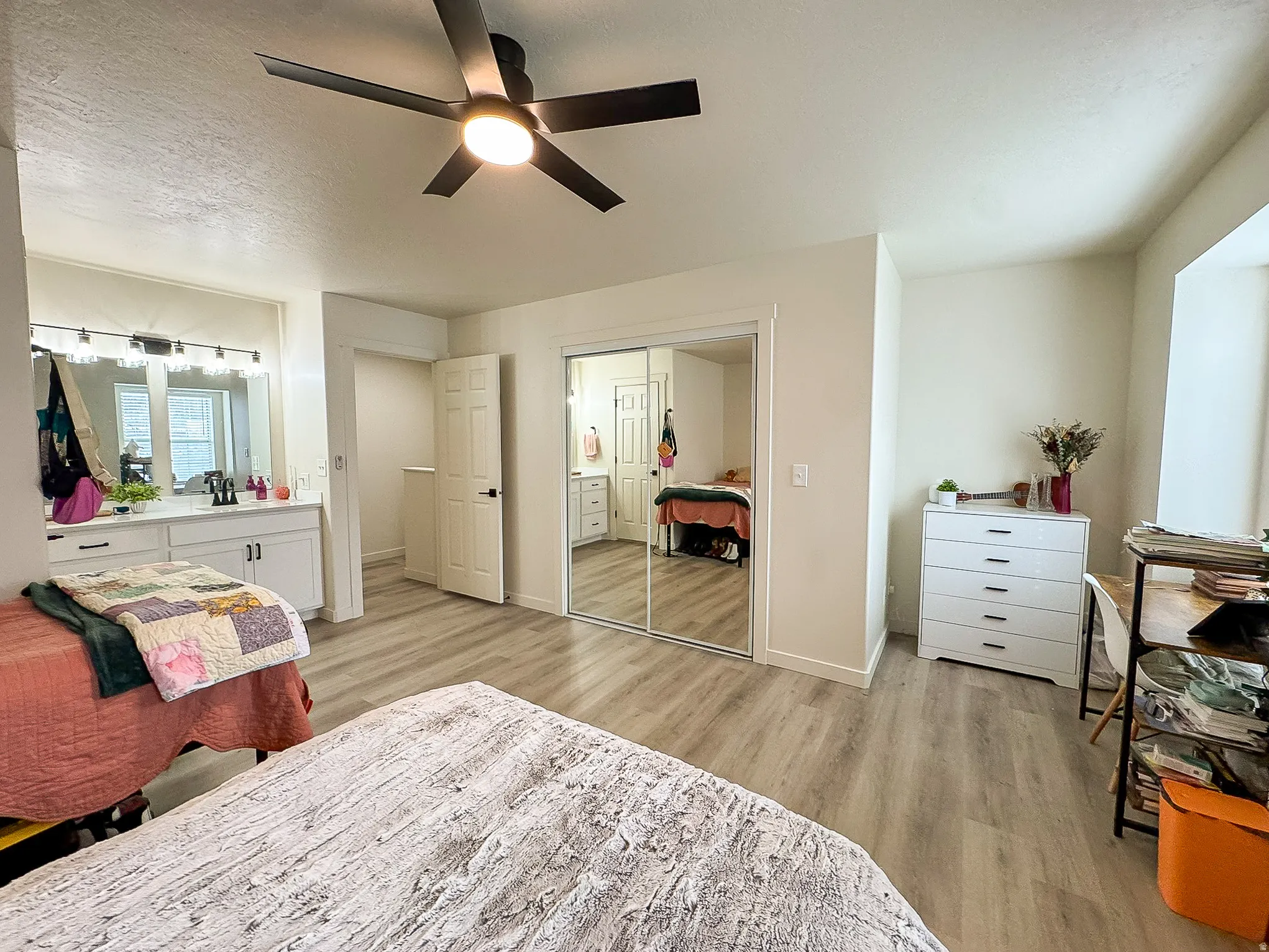 Bedroom with light wood-style floors, a textured ceiling, ceiling fan, and a closet