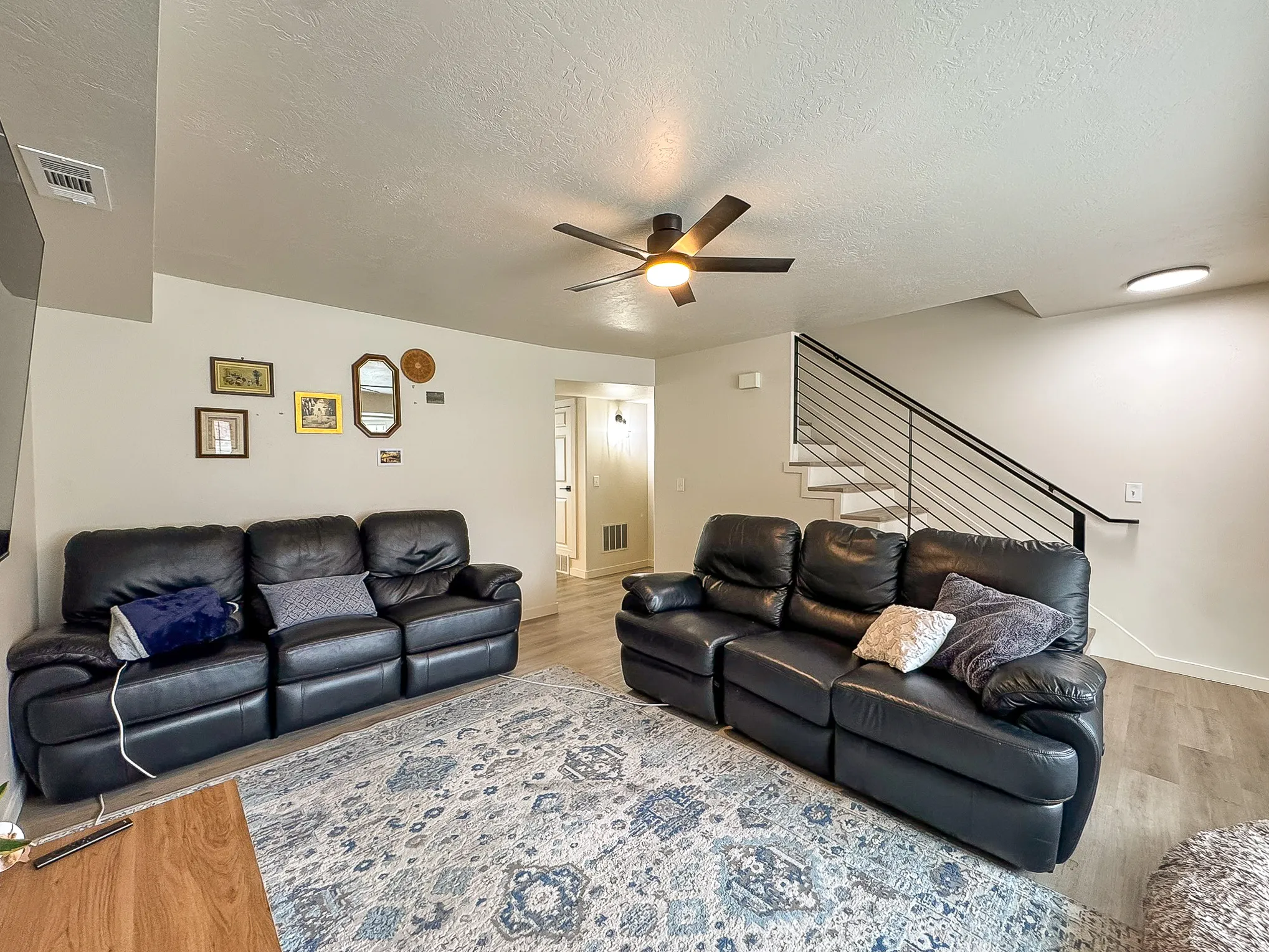 Living room featuring a ceiling fan, a textured ceiling, and light wood finished floors
