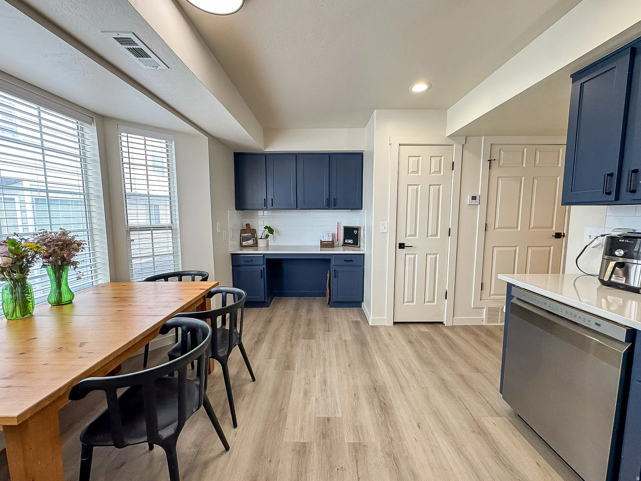 Kitchen featuring blue cabinets, dishwasher, light wood-style floors, tasteful backsplash, and recessed lighting
