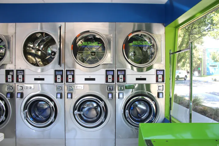 On-site laundry facilities featuring a bank of commercial-grade washers and matching dryer units with stainless steel construction and individual coin or card-operated controls