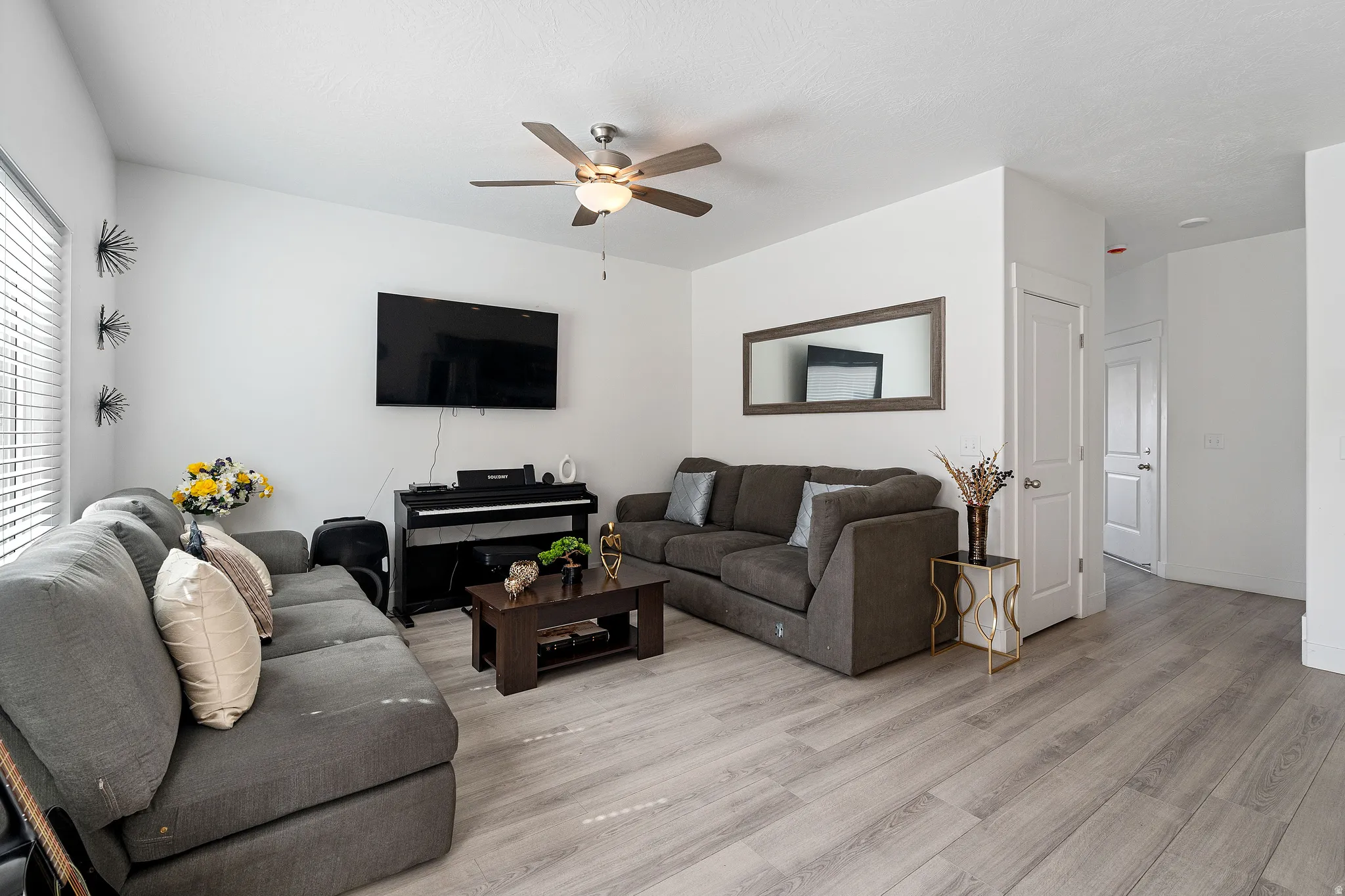 Living room featuring light wood-type flooring and a ceiling fan
