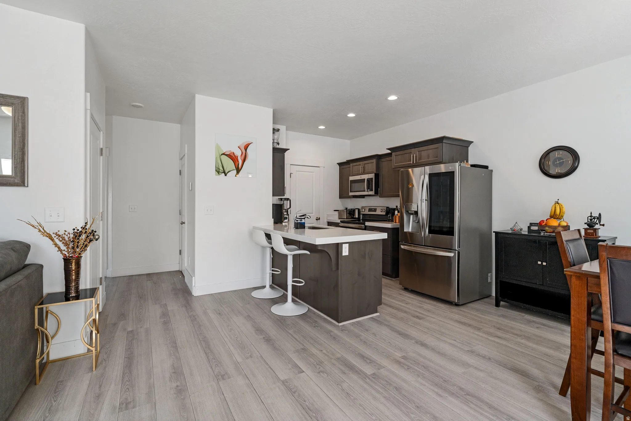 Kitchen featuring a breakfast bar area, light countertops, stainless steel appliances, a peninsula, and dark wood finish cabinetry