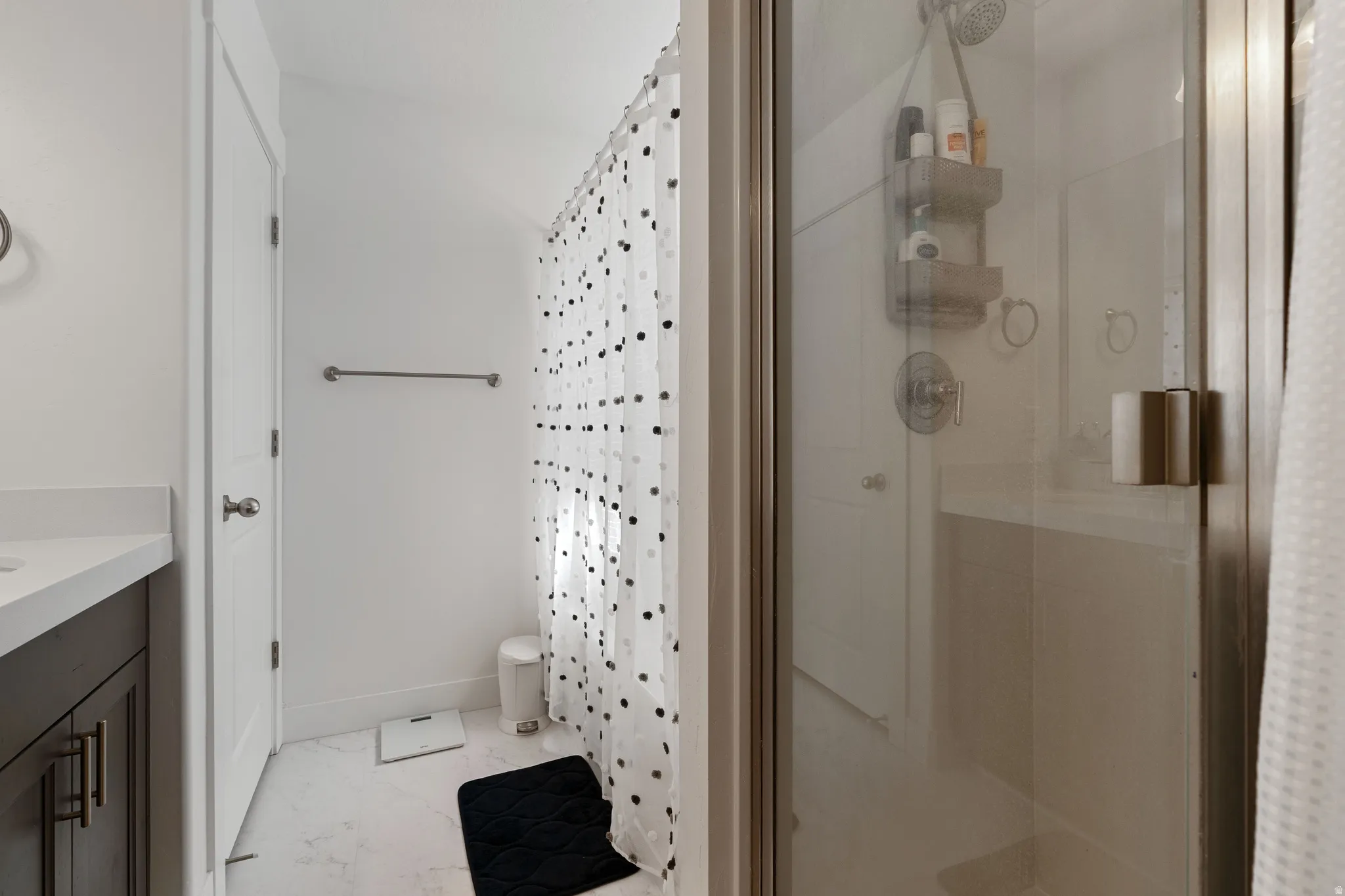 Full bath with a shower stall, vanity, and light marble finish flooring