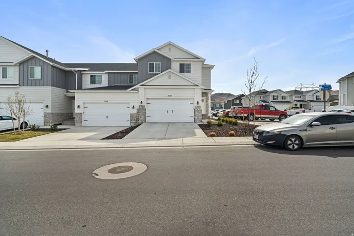 View of front of property featuring board and batten siding, stone siding, a residential view, concrete driveway, and a garage