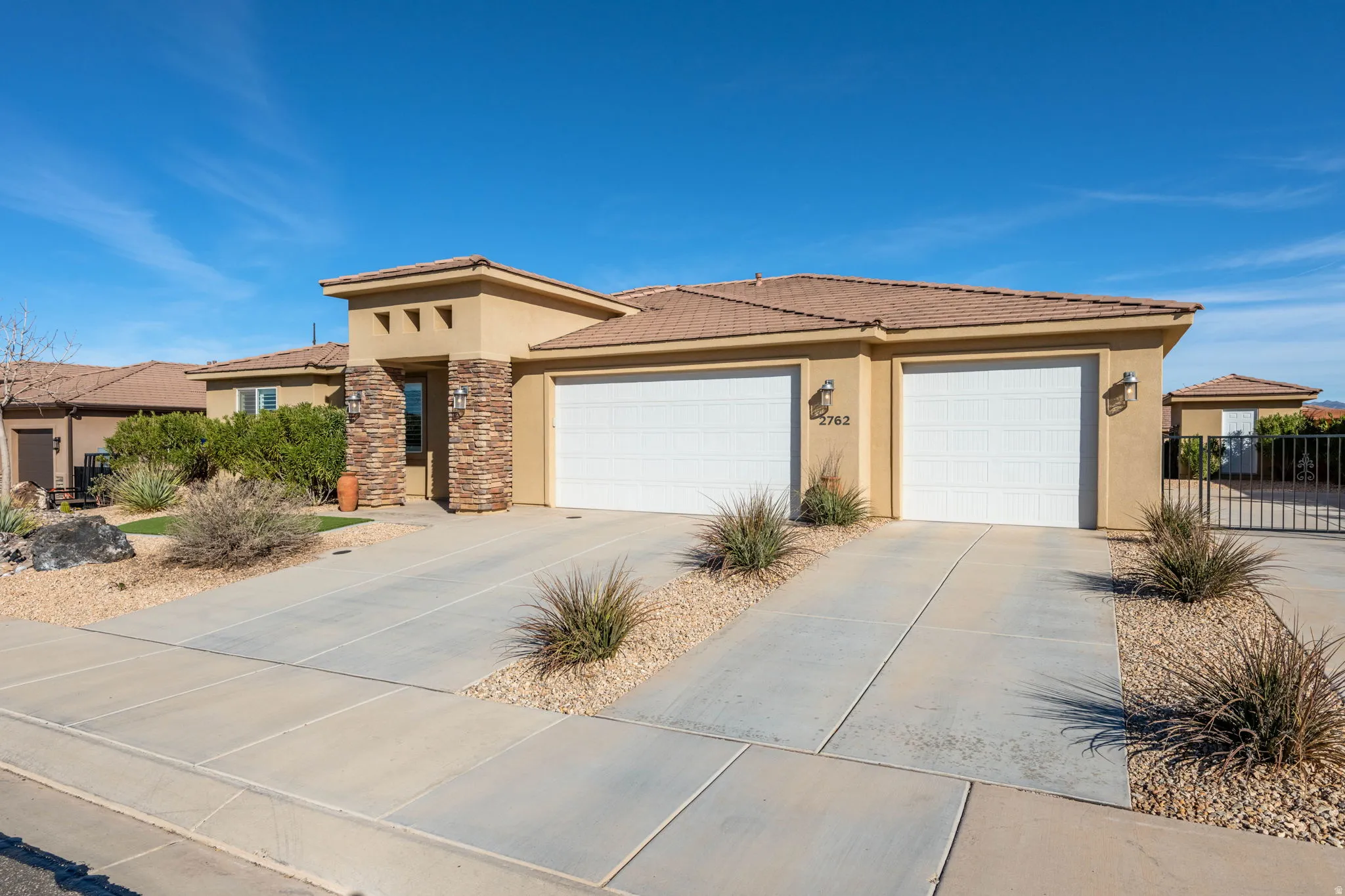 Prairie-style home with stucco siding, an attached garage, concrete driveway, and a tile roof