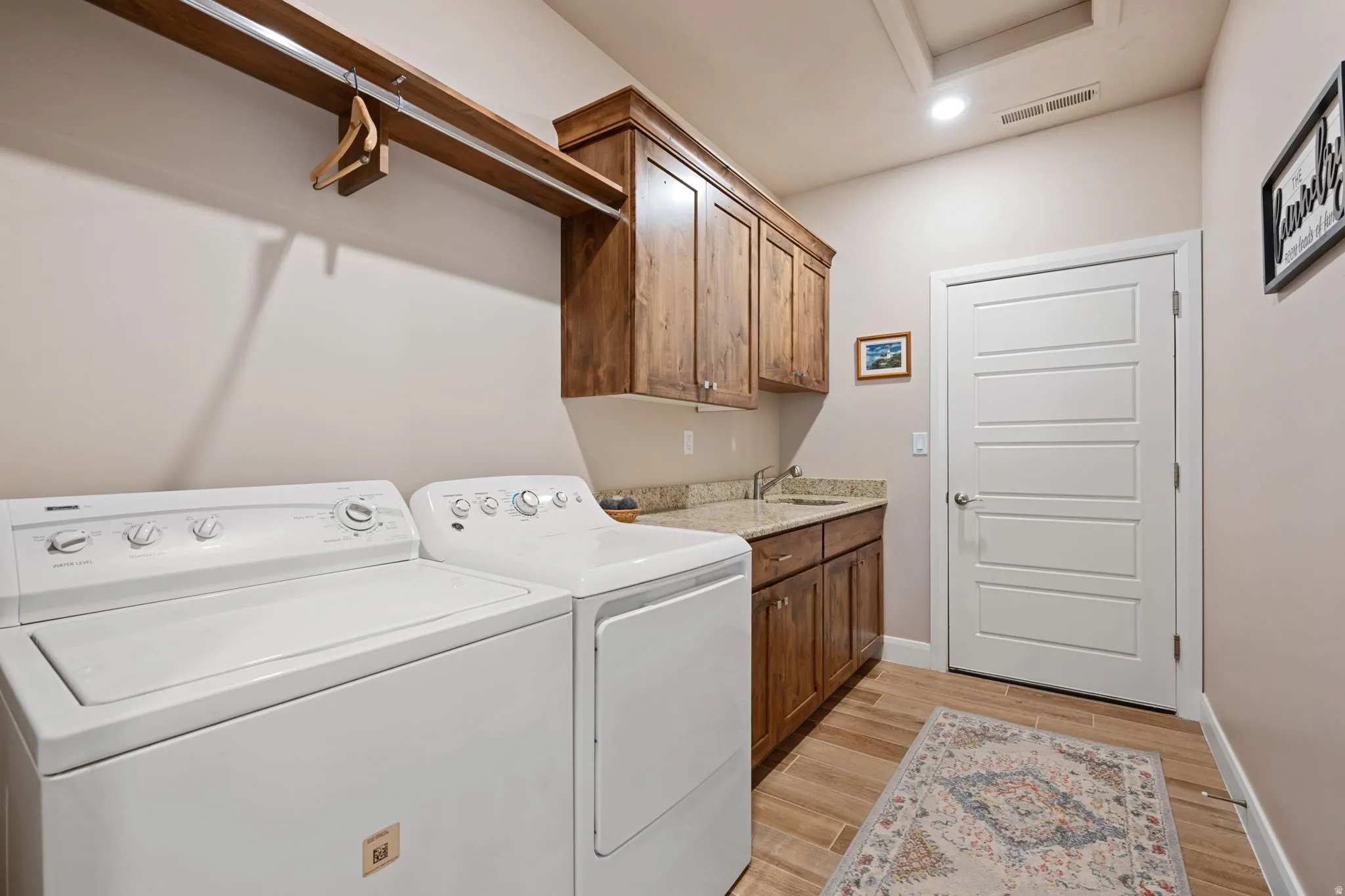 Laundry room with washing machine and dryer, light wood-type flooring, cabinet space, and recessed lighting