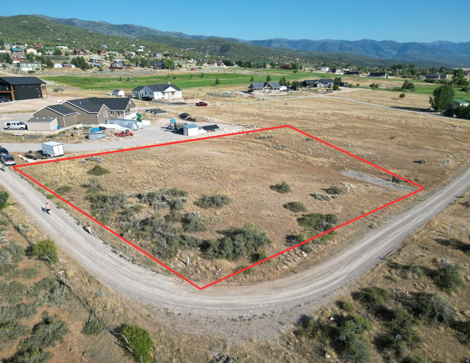 Aerial view of property and surrounding area featuring property boundaries highlighted and a mountainous background