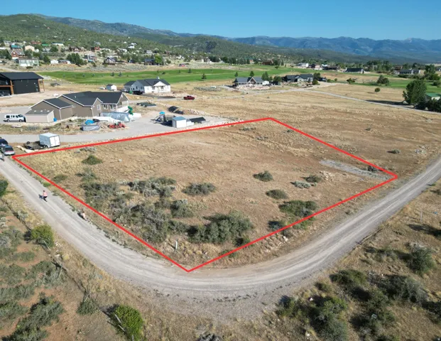 Aerial view of property and surrounding area featuring property boundaries highlighted and a mountainous background