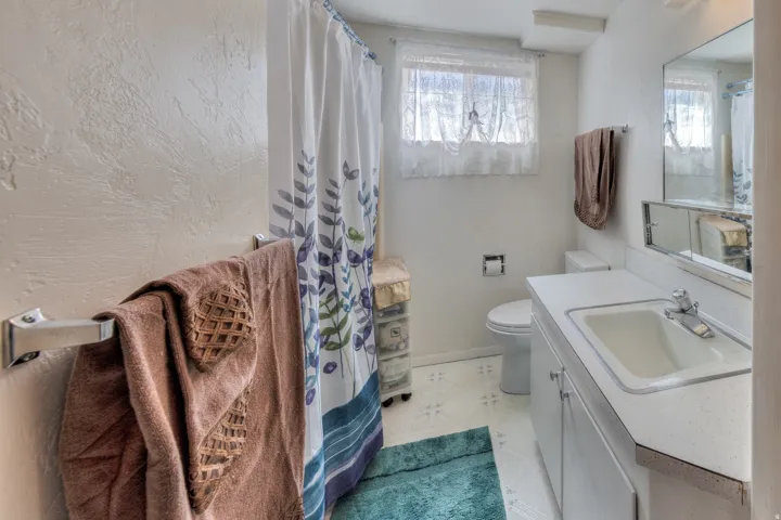 Full bathroom with vanity, a shower with curtain, plenty of natural light, and a textured wall
