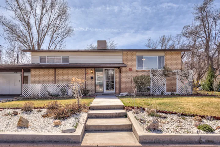 Tri-level home featuring a front yard, brick siding, and a chimney