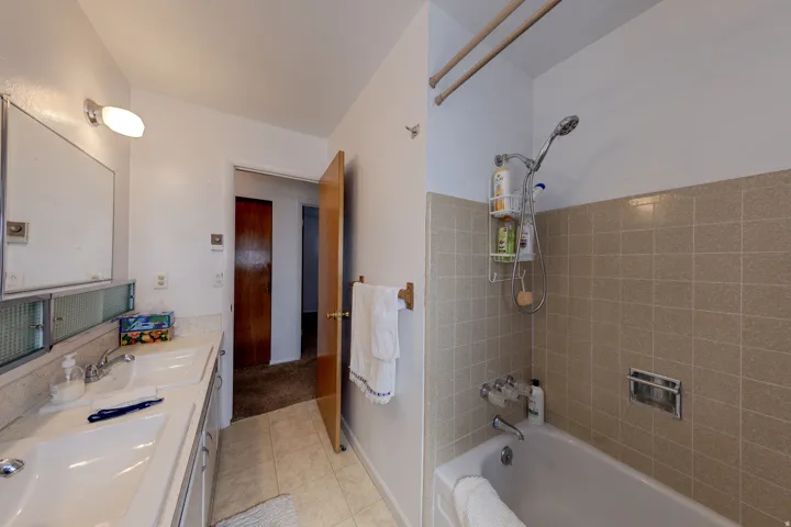 Full bath with double vanity, bathing tub / shower combination, and light tile patterned floors