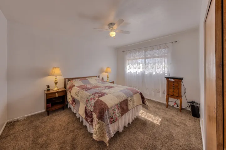 Bedroom featuring a ceiling fan and dark carpet