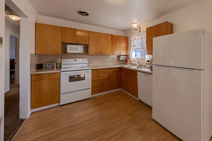 Kitchen featuring white appliances, light countertops, backsplash, and light wood-type flooring