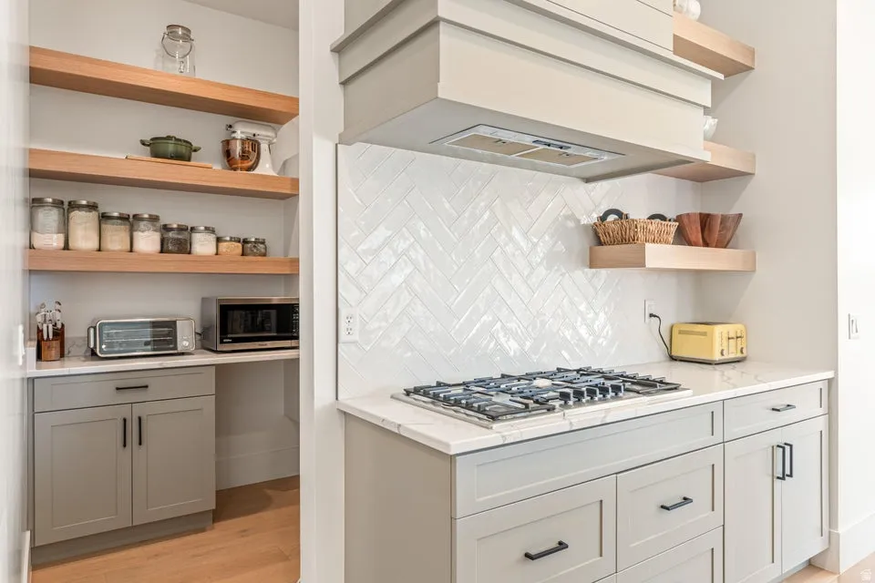 Kitchen with open shelves, light stone countertops, backsplash, stainless steel appliances, and light wood-type flooring