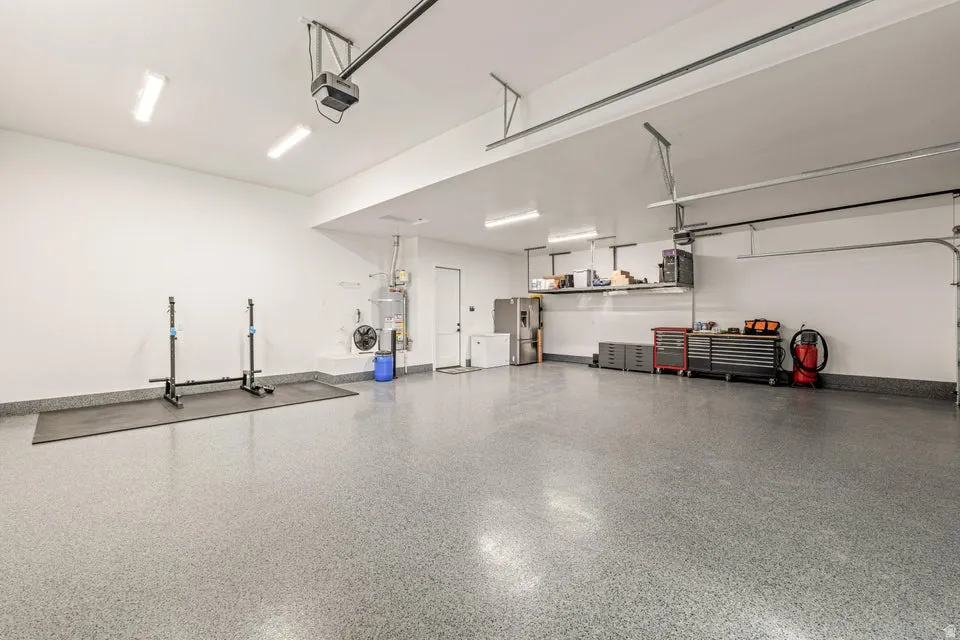 Garage featuring stainless steel refrigerator with ice dispenser, strapped water heater, and a garage door opener