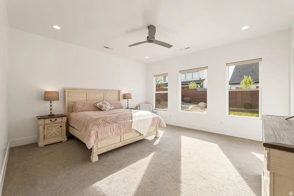 Bedroom with light carpet, ceiling fan, and recessed lighting