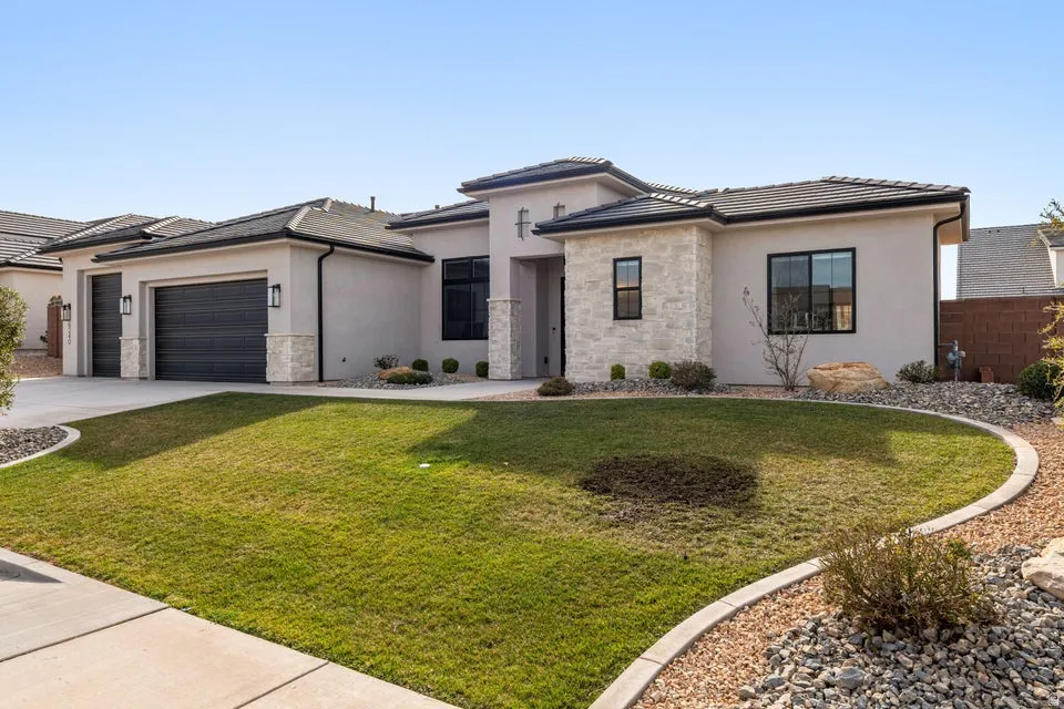 Prairie-style home featuring stone siding, stucco siding, an attached garage, driveway, and a tiled roof