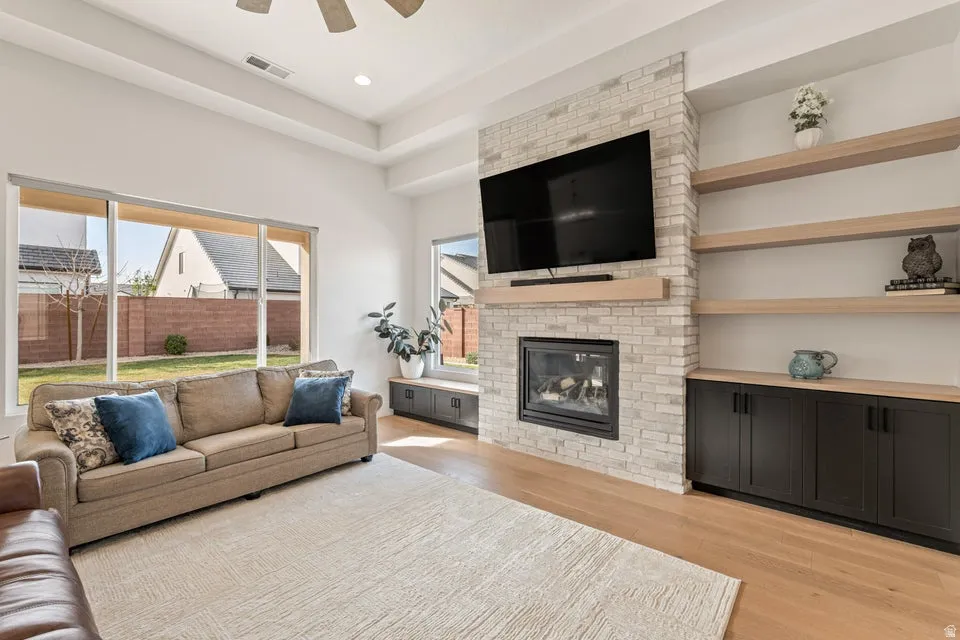 Living area with a fireplace, a ceiling fan, light wood-style flooring, and recessed lighting