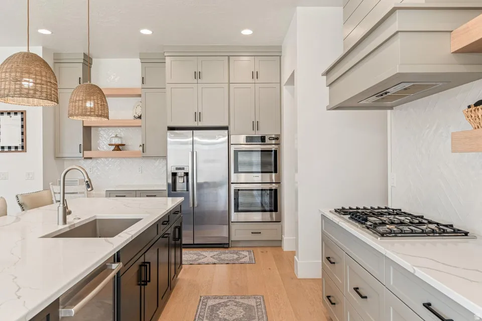 Kitchen featuring decorative backsplash, stainless steel appliances, light stone countertops, light wood-style floors, and open shelves