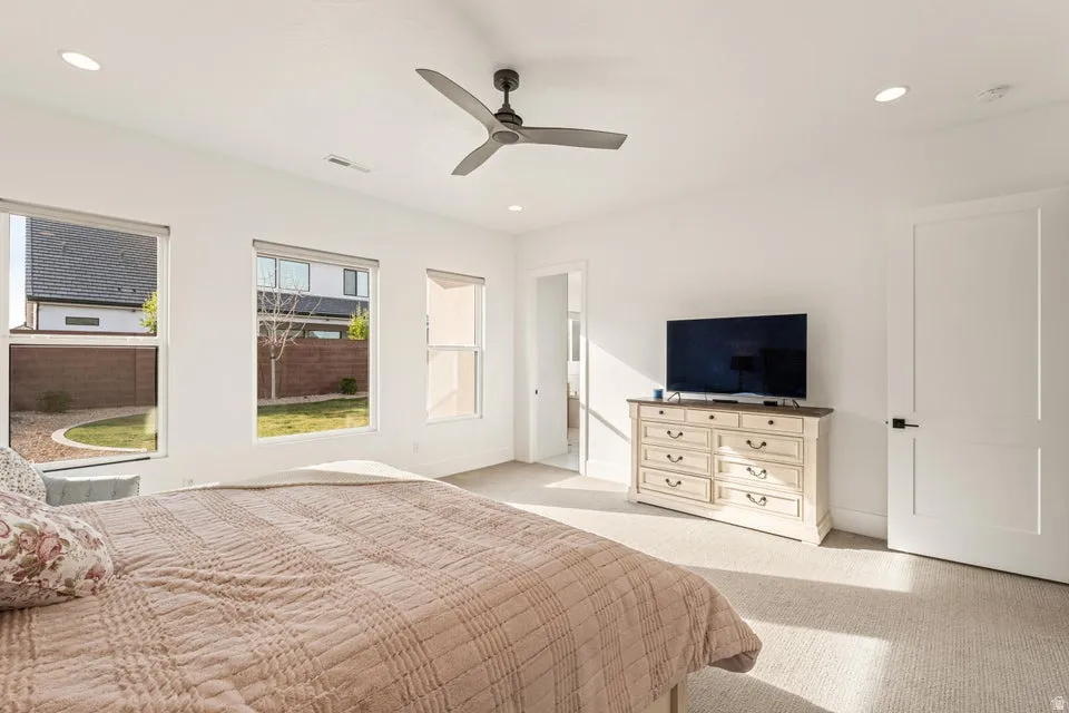 Bedroom featuring light colored carpet, ceiling fan, and recessed lighting