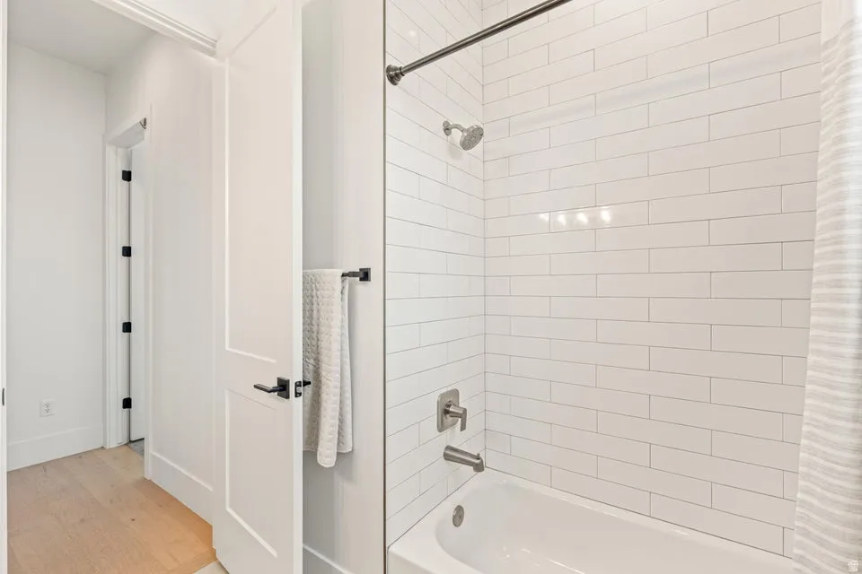 Bathroom featuring shower / bath combination with curtain and light wood finished floors