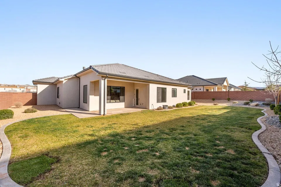 Rear view of house with a fenced backyard, a patio area, and stucco siding