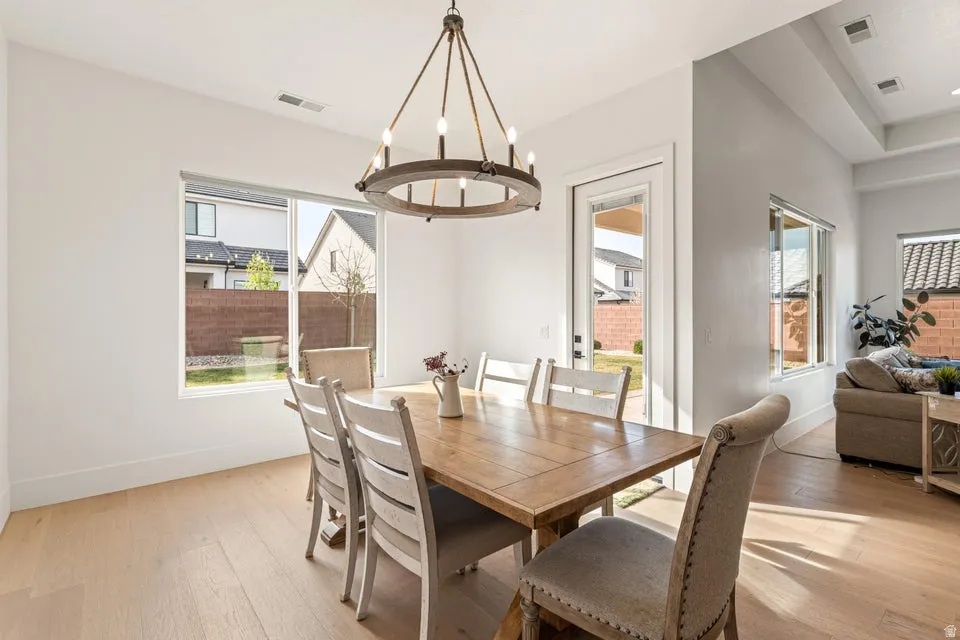 Dining area with light wood-style flooring, plenty of natural light, and a chandelier