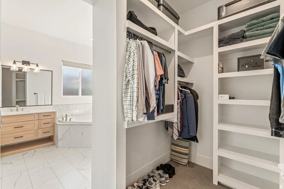 Walk in closet with light marble finish floors and a sink