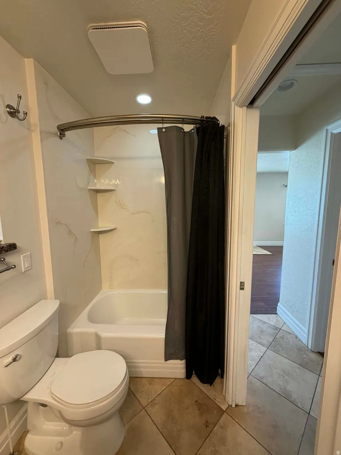 Full bath with shower / bath combo with shower curtain, a textured ceiling, and light tile patterned floors