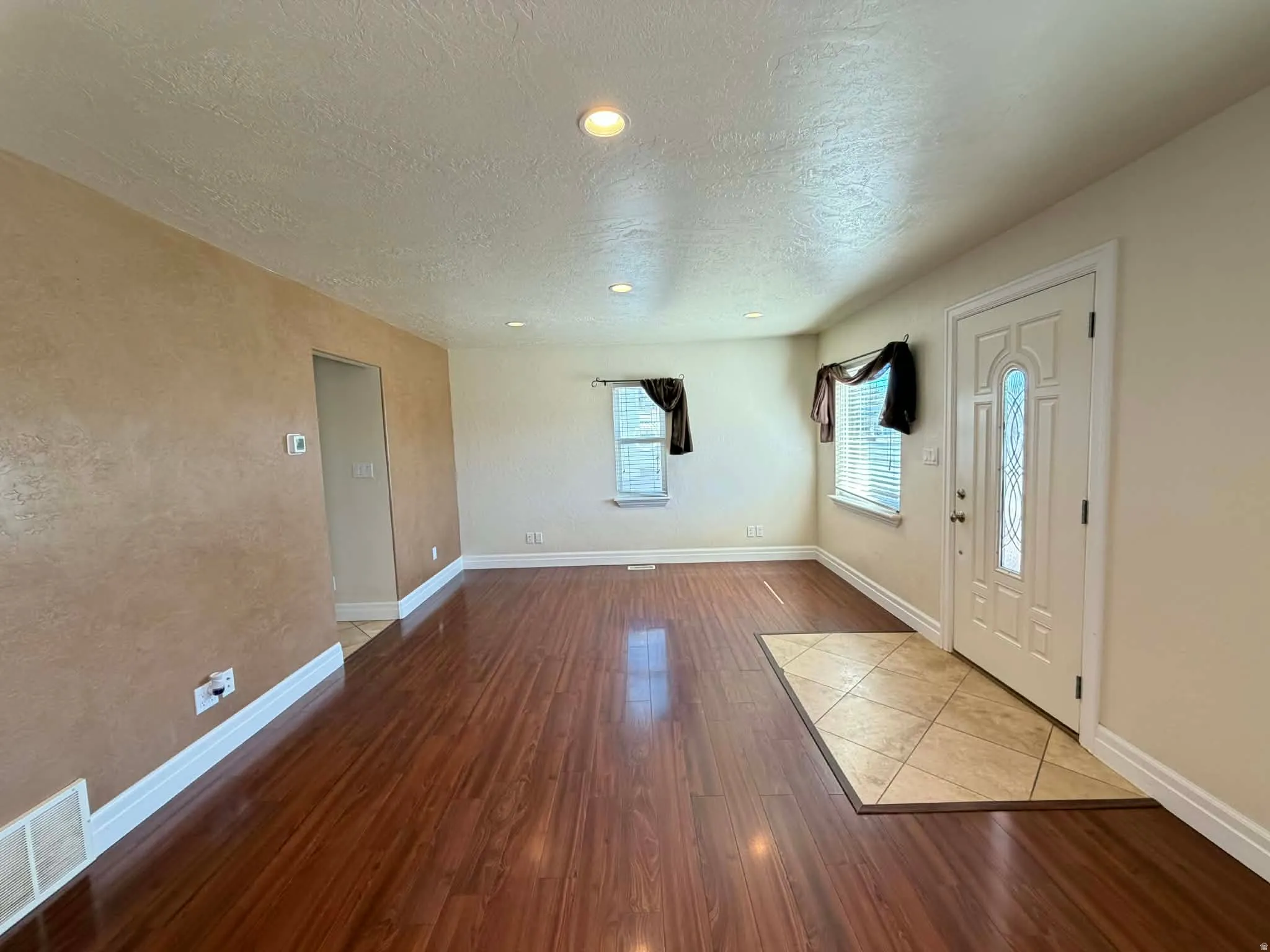 Foyer with dark wood-style floors, a textured ceiling, a textured wall, and recessed lighting