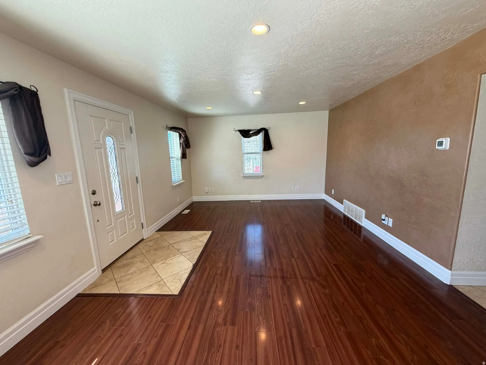 Entryway with dark wood-style flooring, recessed lighting, a textured ceiling, and a textured wall