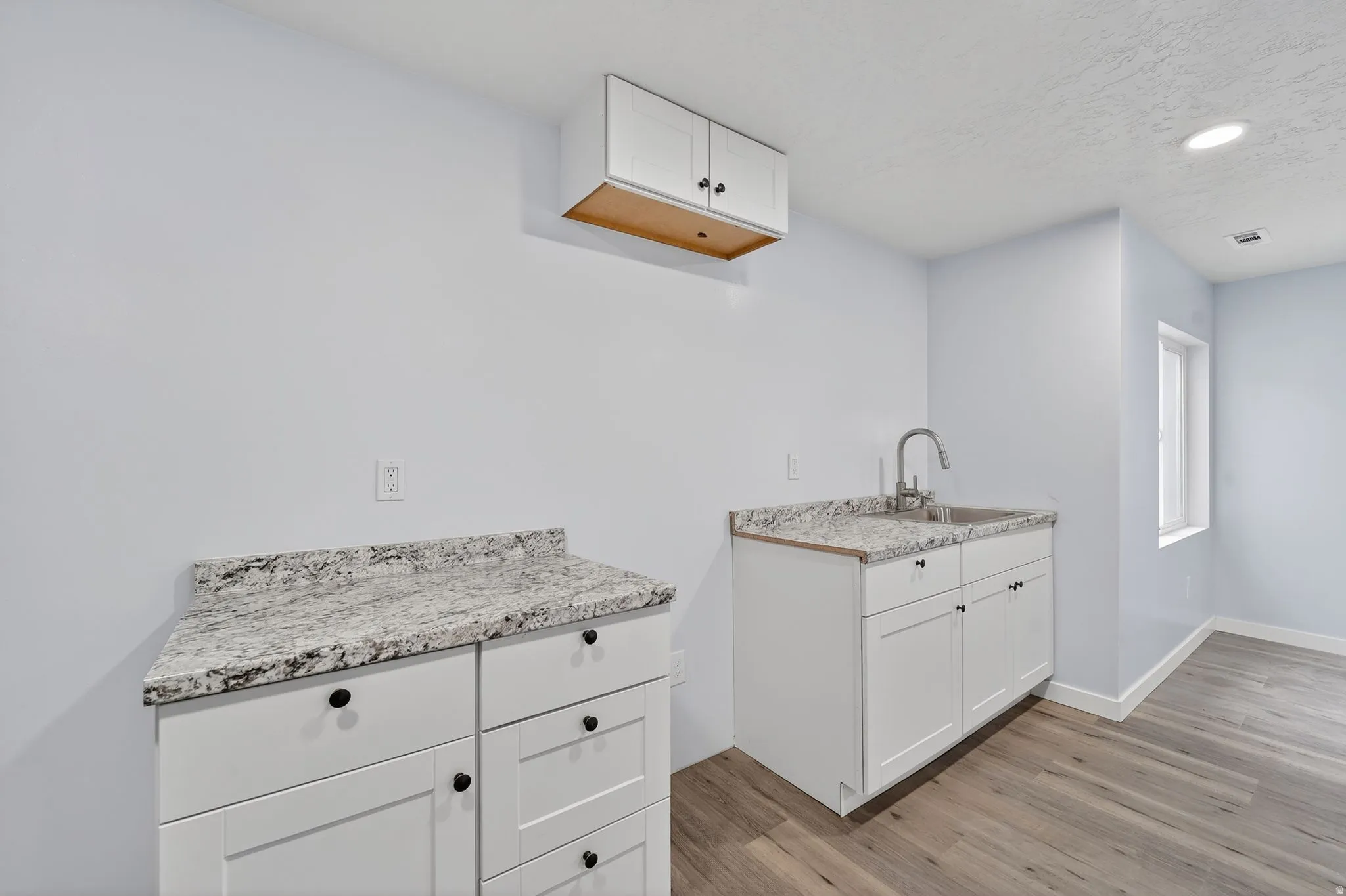 Kitchen featuring white cabinets, light wood-style floors, recessed lighting, and a textured ceiling