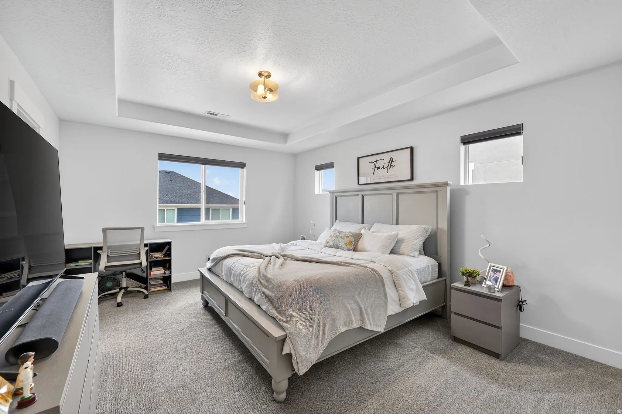 Carpeted bedroom with a tray ceiling and a textured ceiling