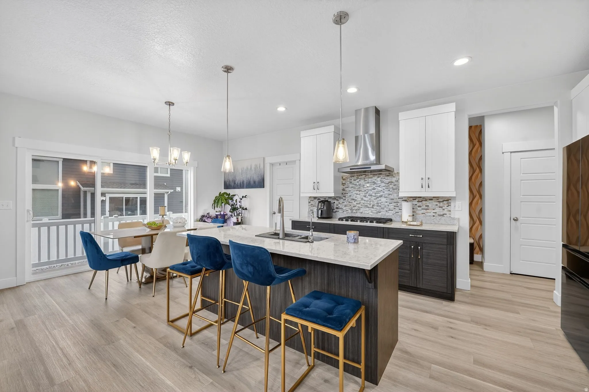 Dual tone kitchen featuring dual tone cabinets, a breakfast bar area, light stone counters, an island with sink, and light wood finished floors
