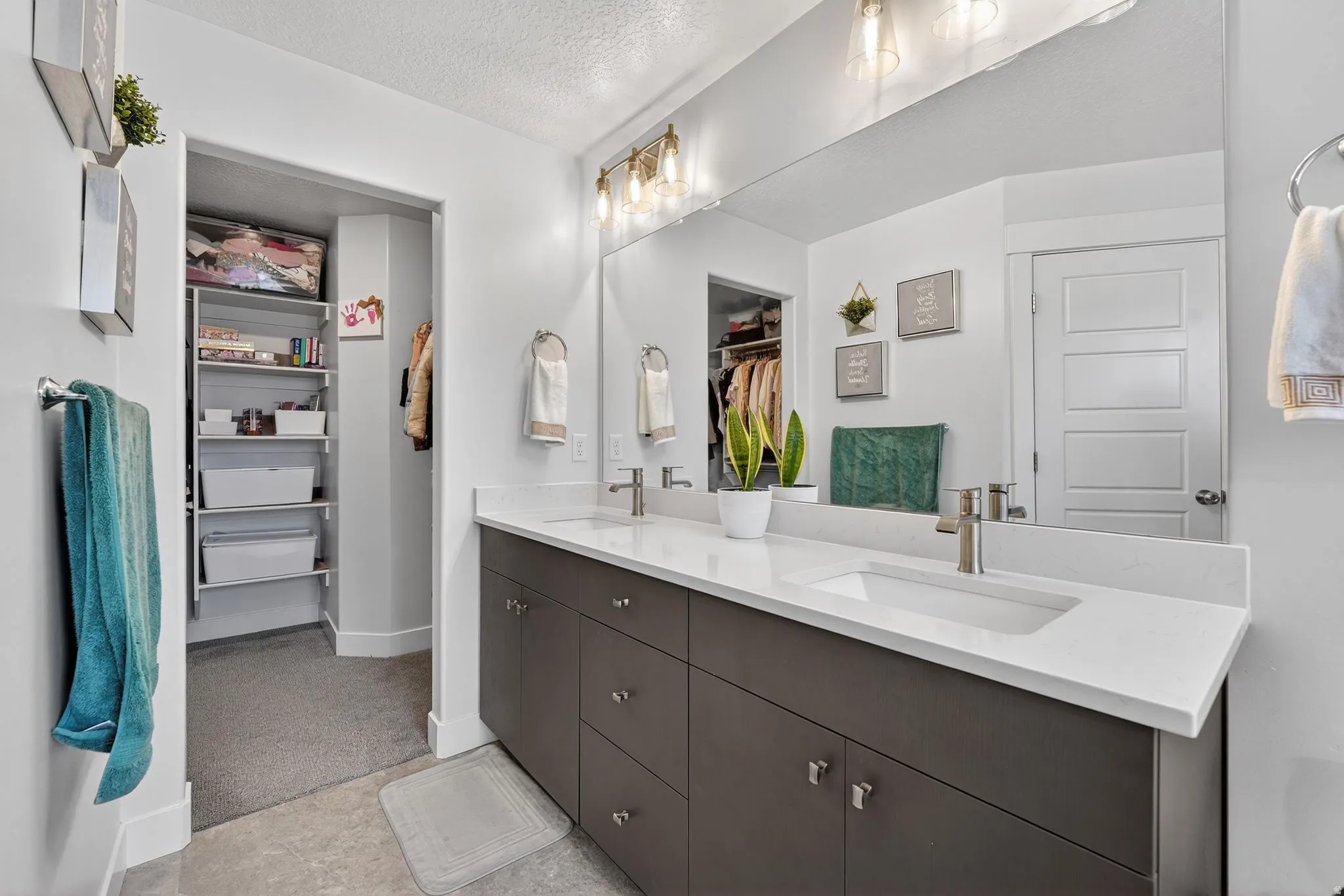 Full bath with a spacious closet, double vanity, and a textured ceiling
