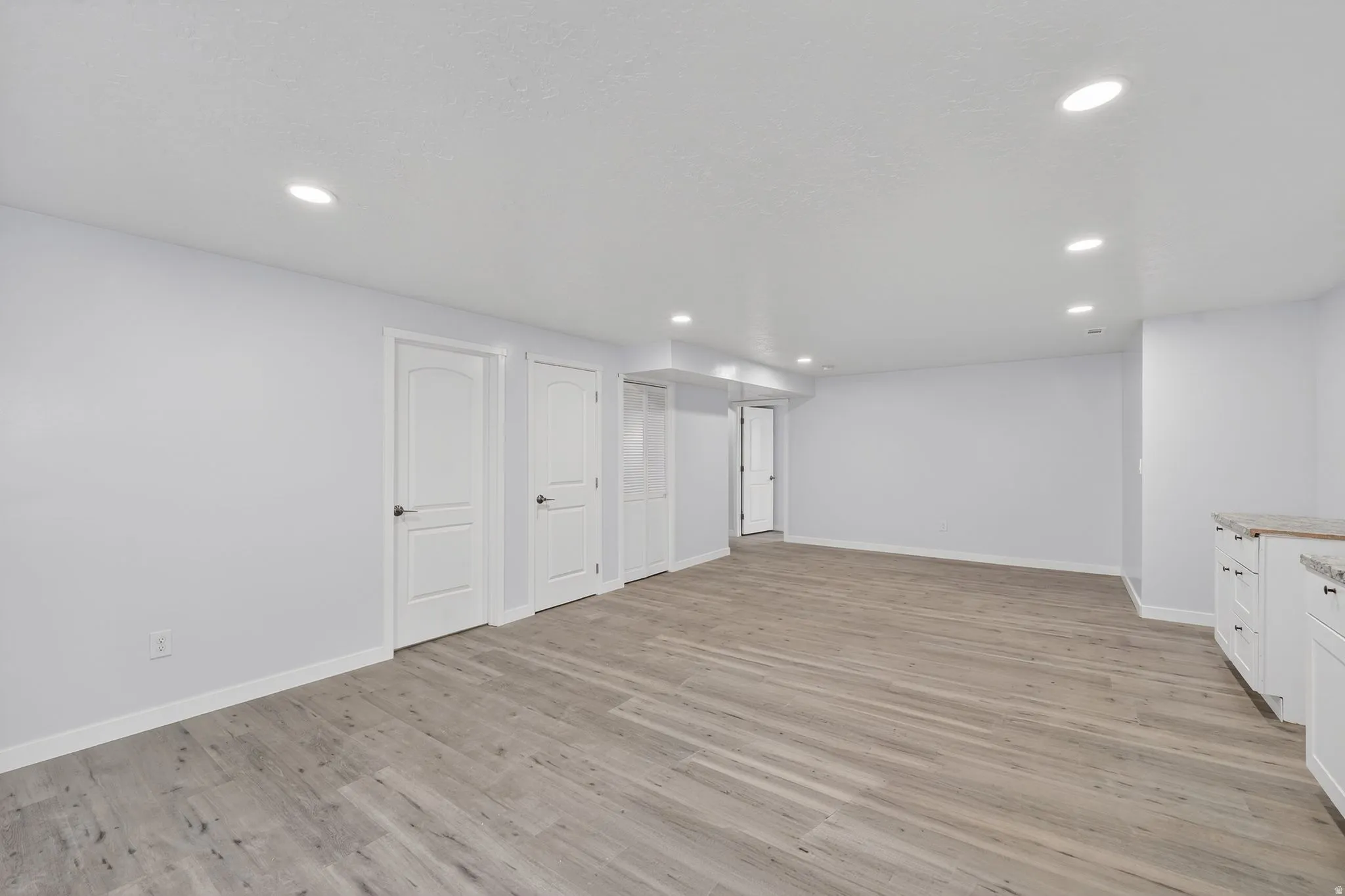 Finished below grade area with light wood-type flooring and recessed lighting