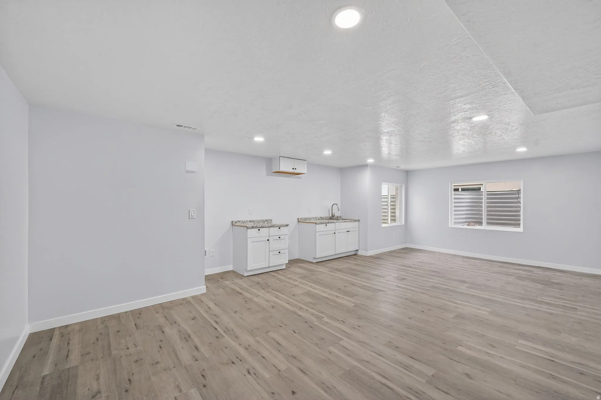 Basement with light wood finished floors, recessed lighting, and a textured ceiling