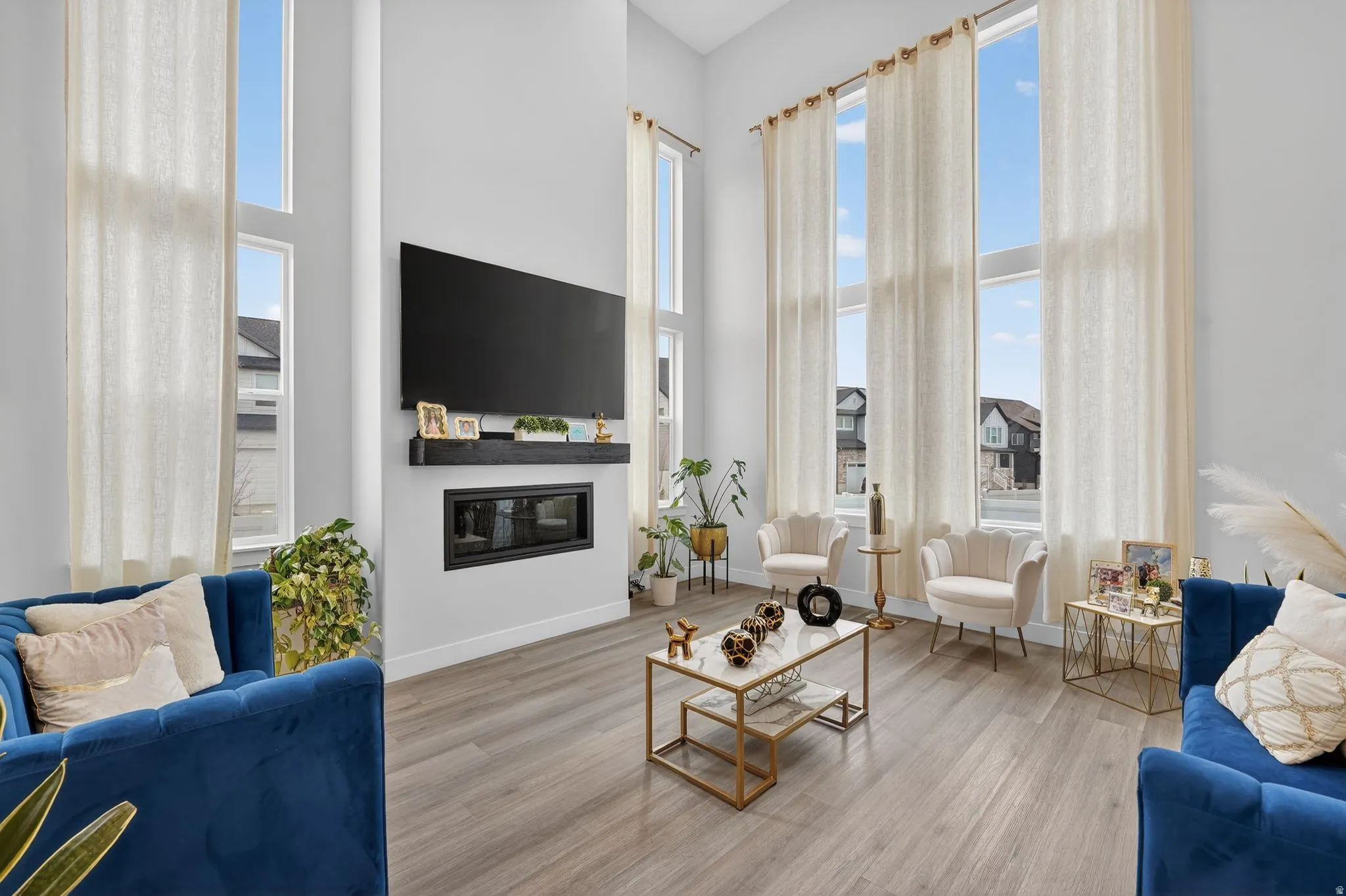 Living area with wood finished floors, a glass covered fireplace, and a high ceiling