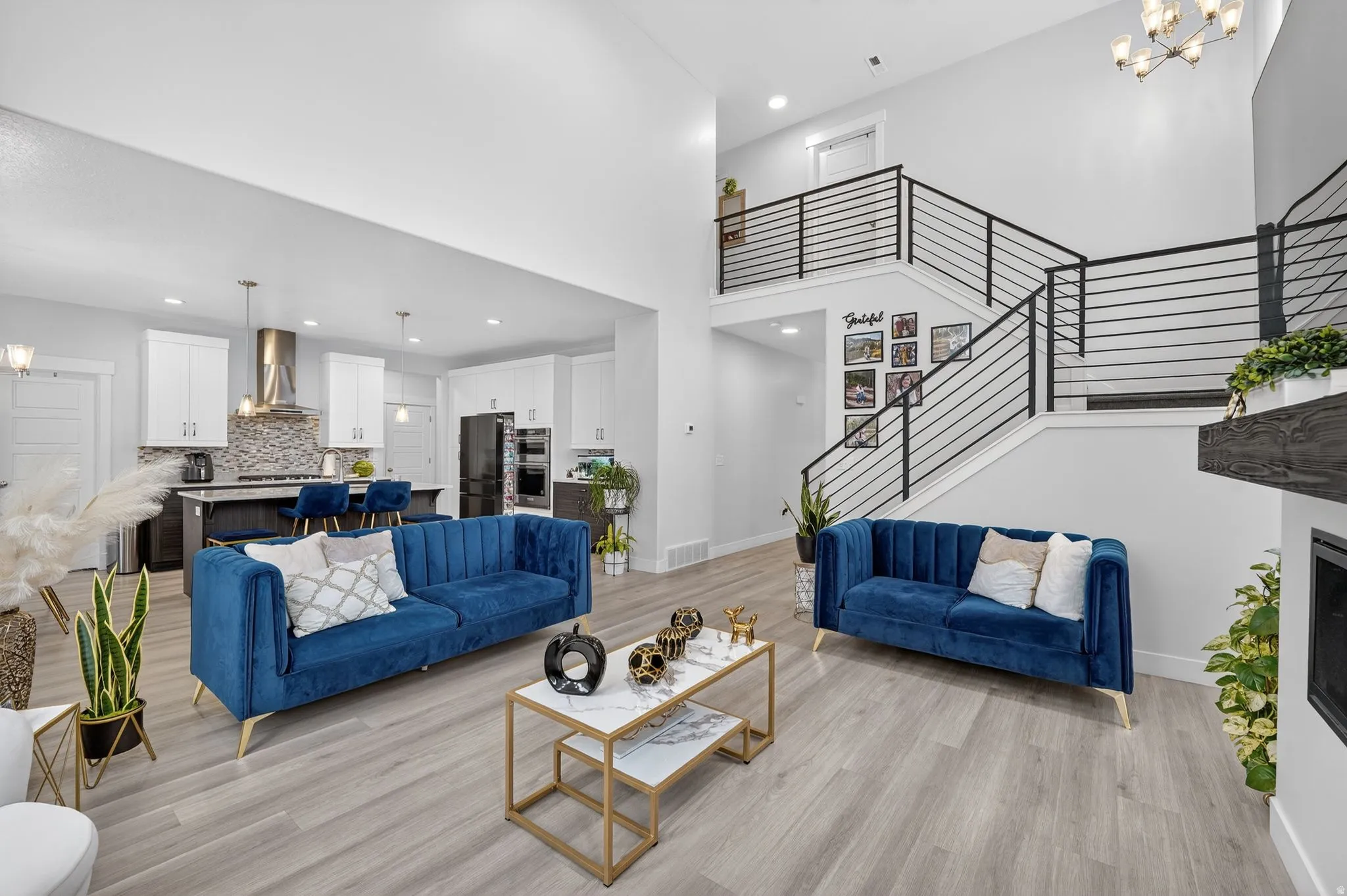 Living area with suspended lighting, light wood-style floors, a fireplace, and a high ceiling