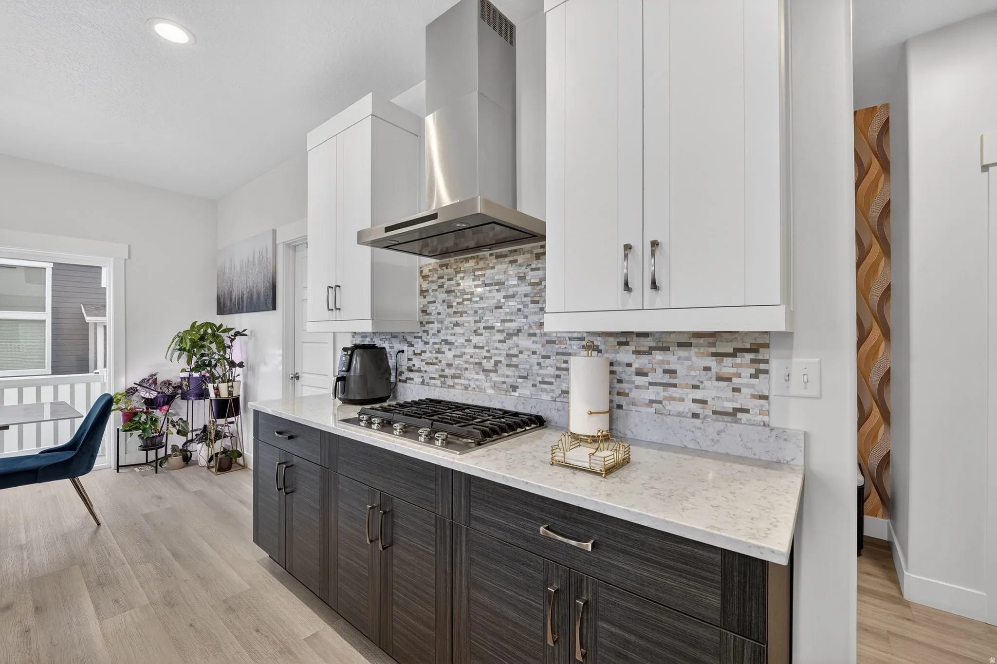 Dual tone kitchen featuring two tone cabinets, light stone countertops, light wood-type flooring, stainless steel gas cooktop, and recessed lighting