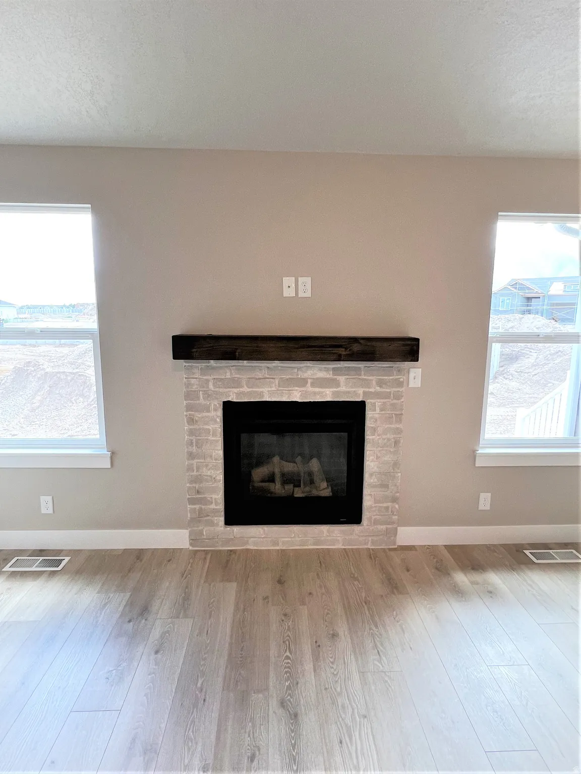Detailed view of wood finished floors, a fireplace, and a textured ceiling