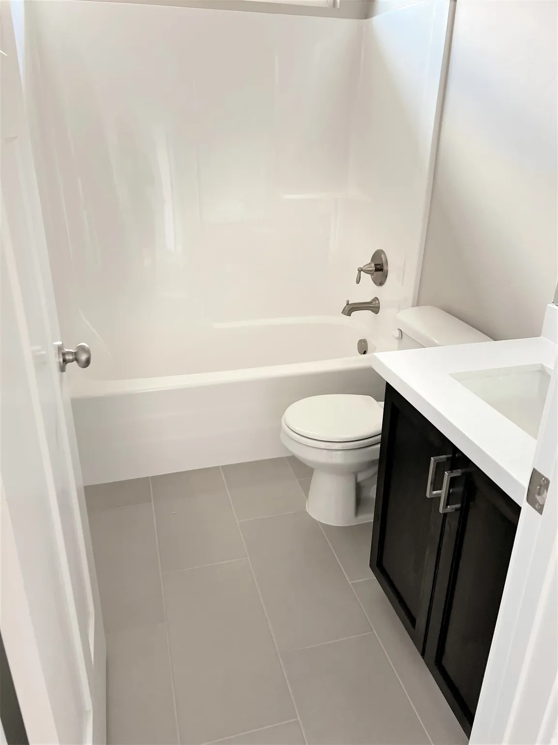 Bathroom featuring vanity, dark tile patterned flooring, and shower / tub combination