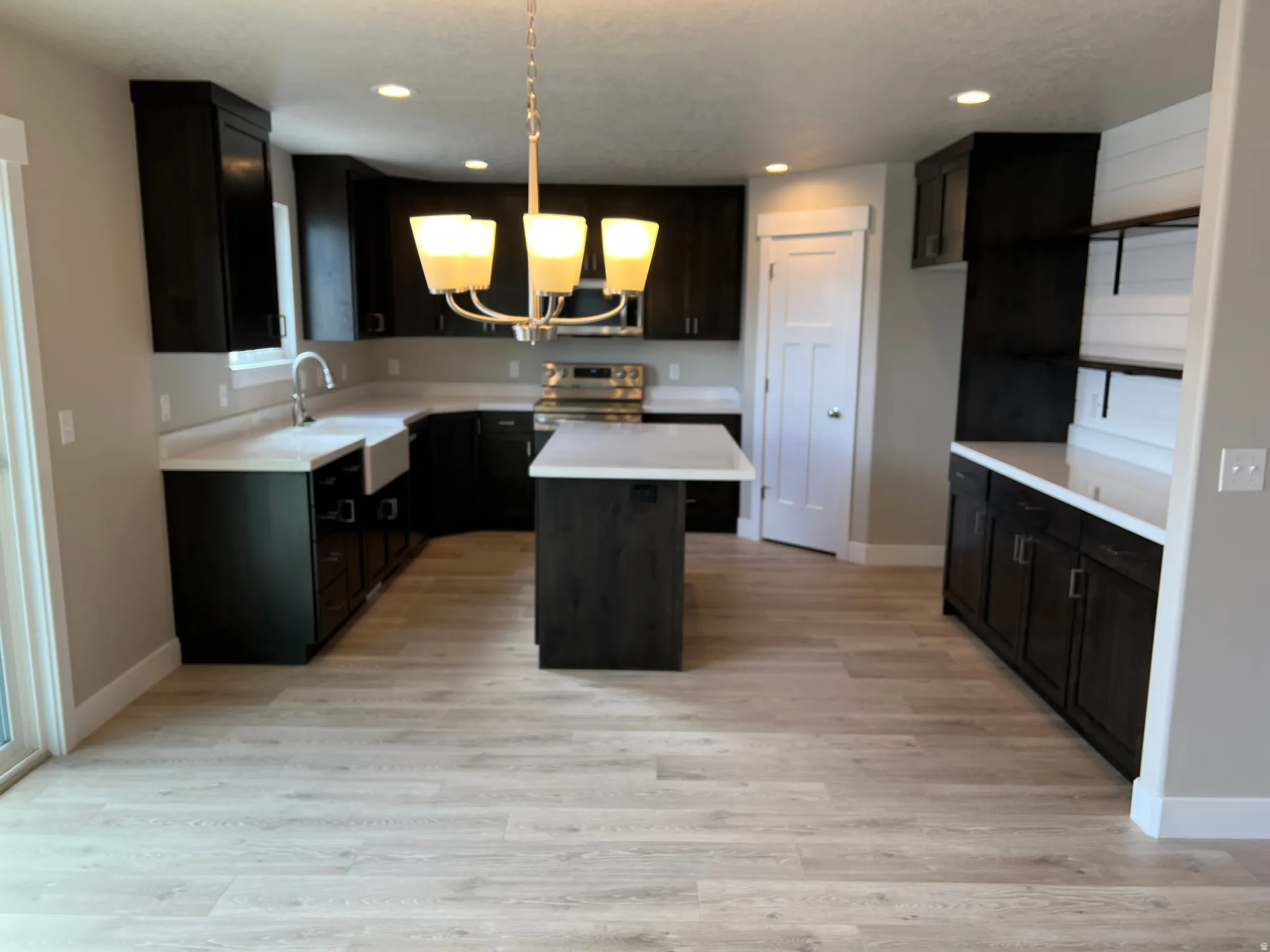 Kitchen featuring light countertops, a kitchen island, stainless steel appliances, and light wood finished floors