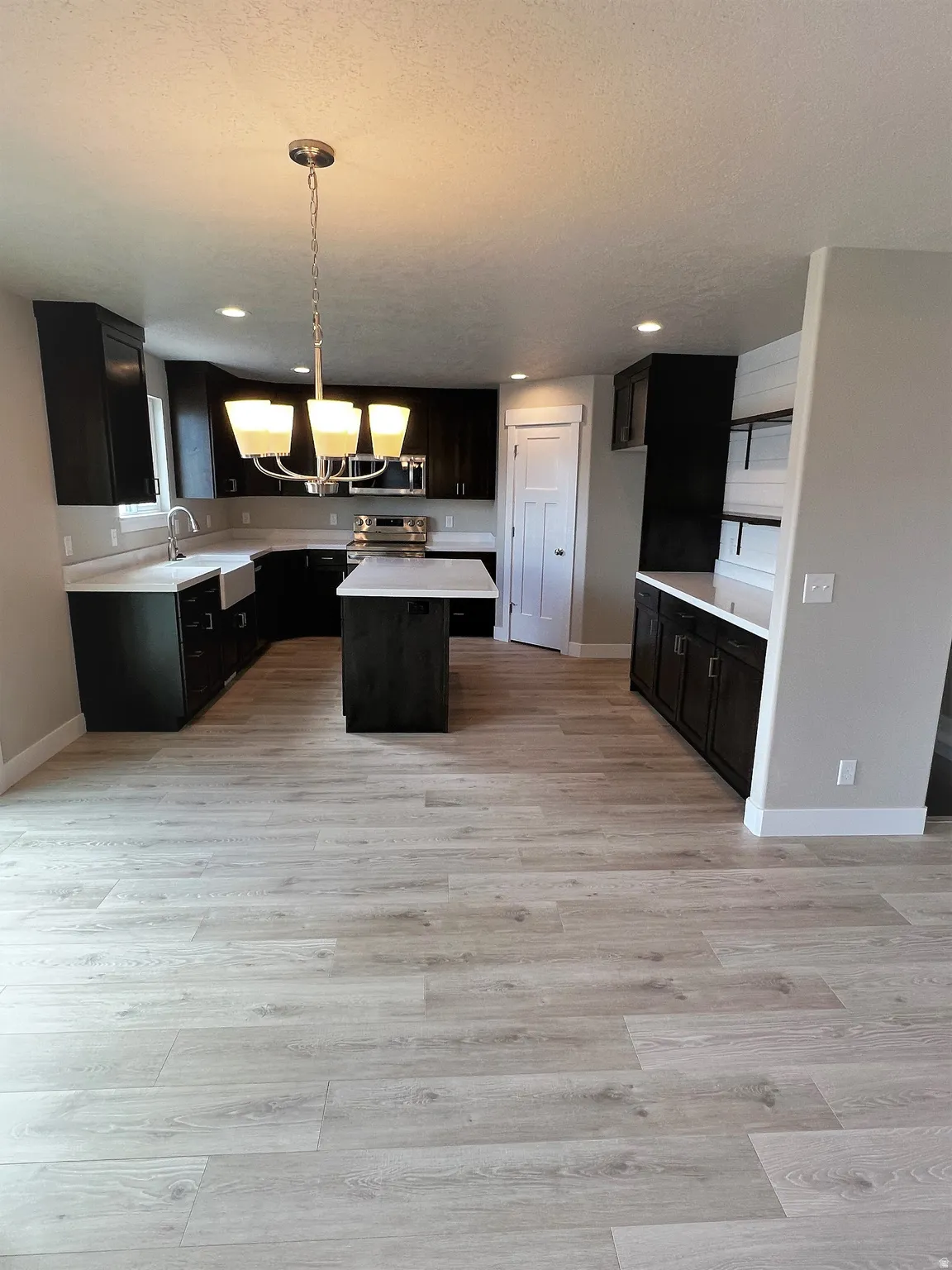 Kitchen with a center island, light countertops, dark cabinets, and a textured ceiling