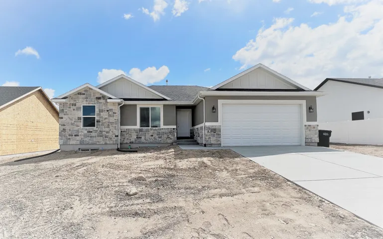 View of front of house featuring board and batten siding, stone siding, driveway, and a garage