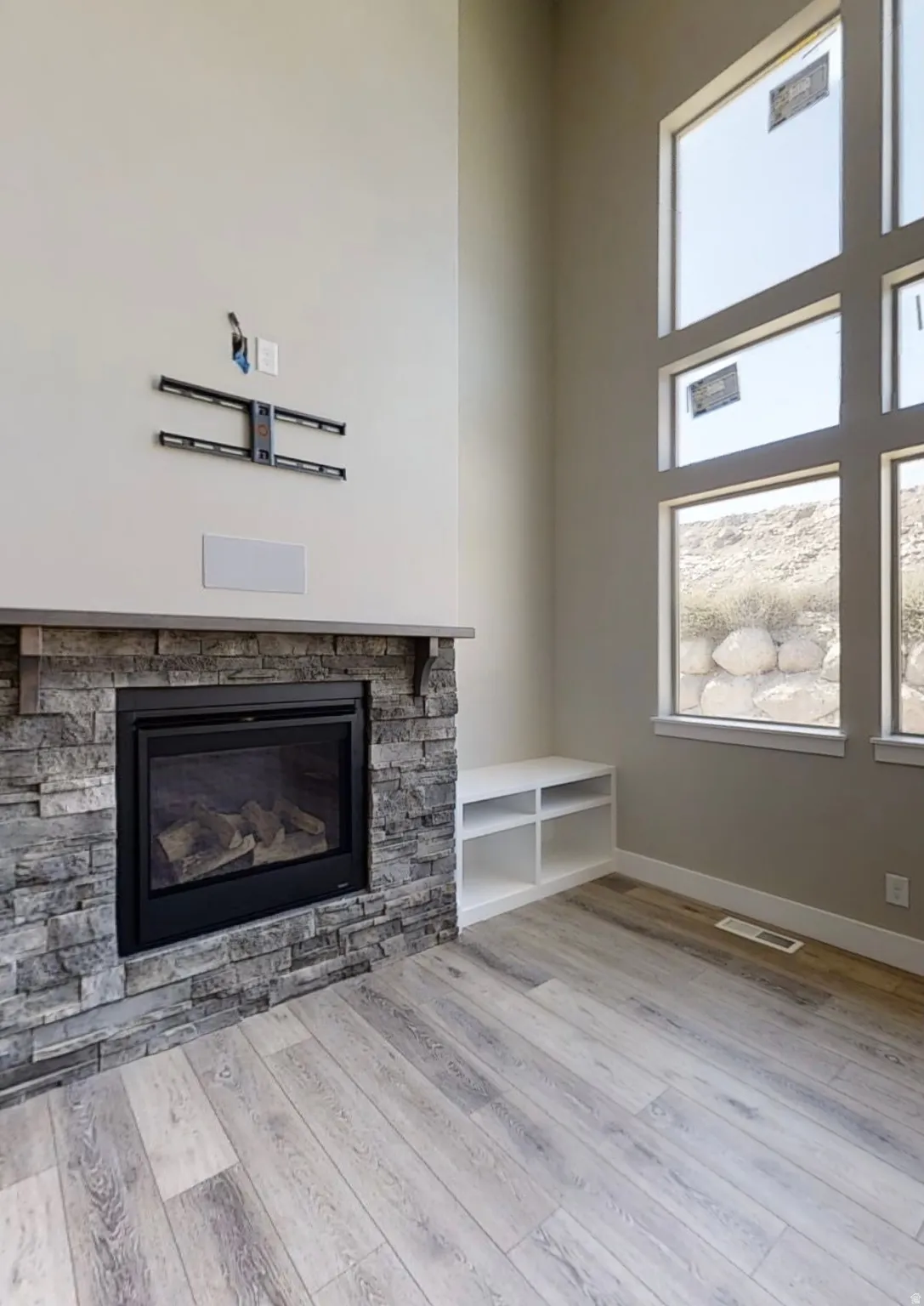 Unfurnished living room with a high ceiling, a fireplace, and light wood-style floors