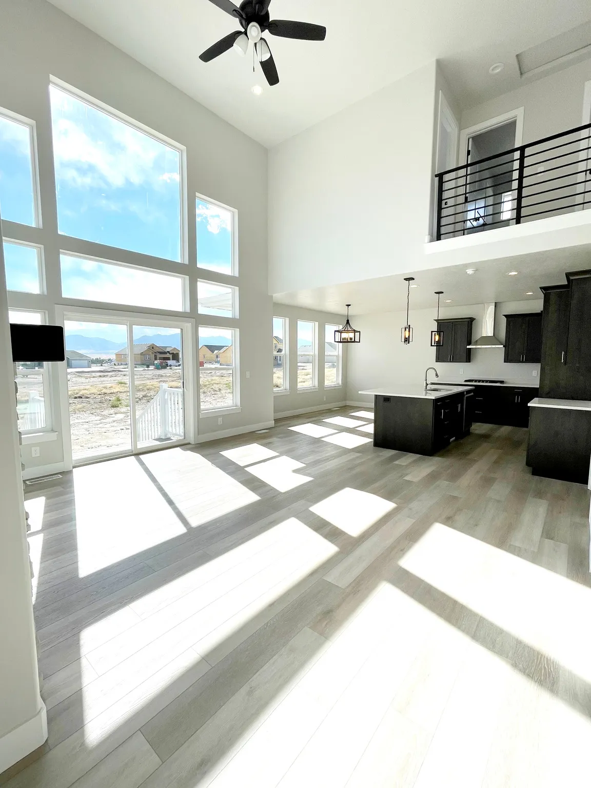 Living room with a high ceiling, a ceiling fan, light wood-type flooring, and recessed lighting