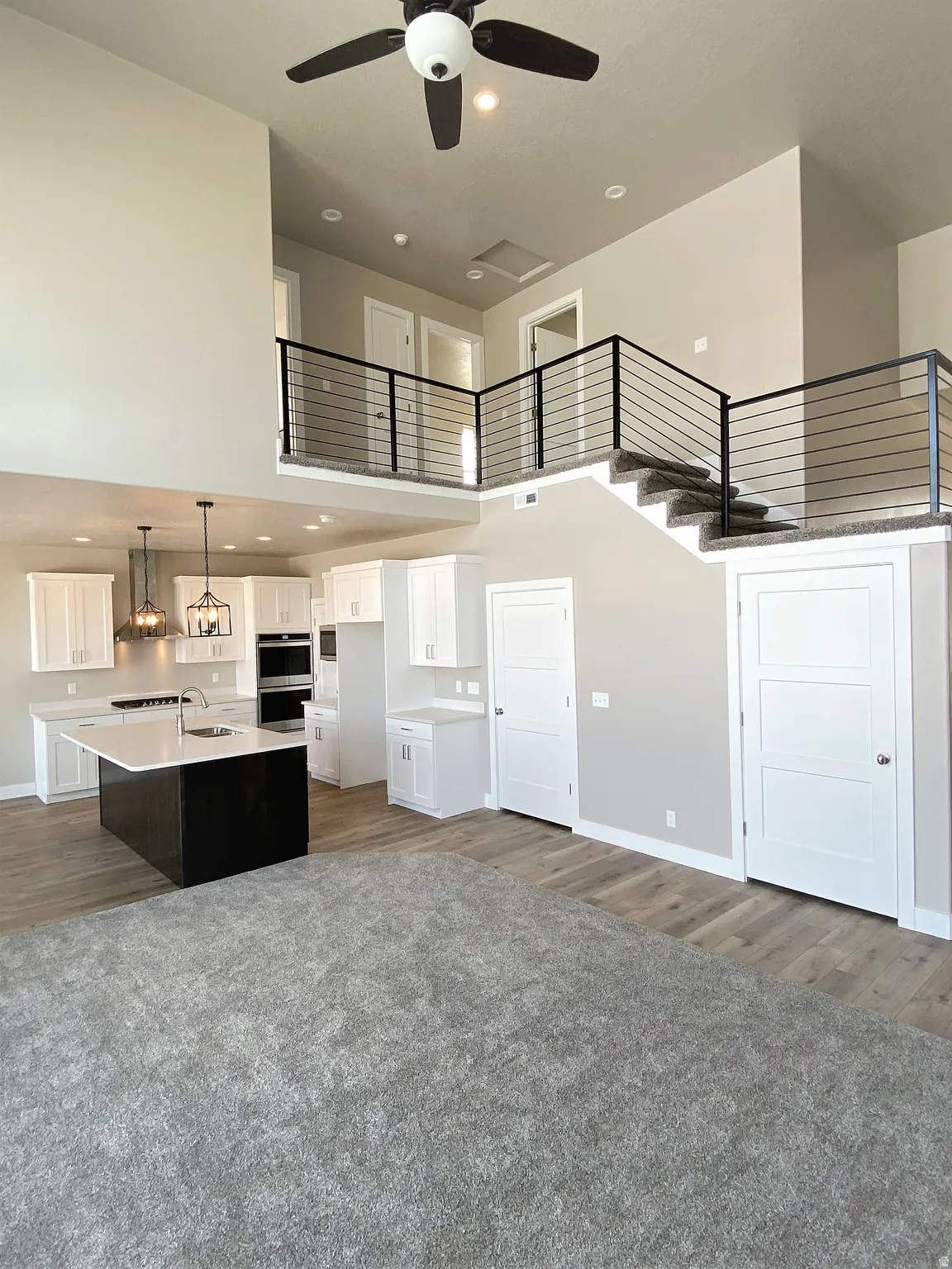 Kitchen with a high ceiling, white cabinetry, open floor plan, dark carpet, and a center island with sink