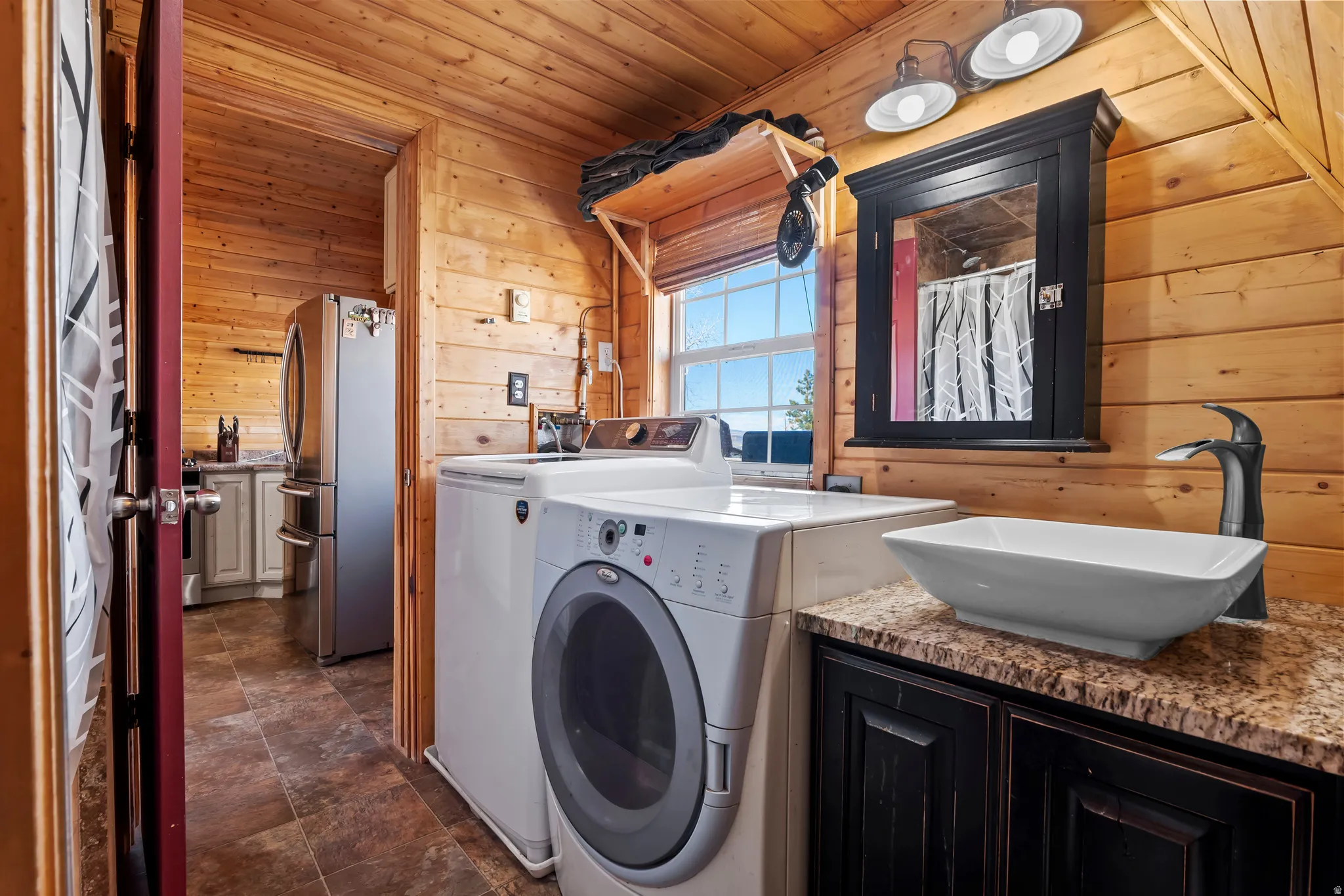 Laundry area & bathroom featuring wood walls, wooden ceiling, washer and clothes dryer, and stone finish flooring